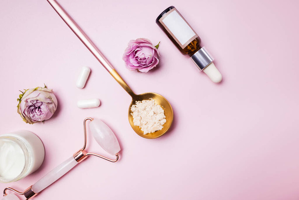 Skincare accessories on pink background. Massage tools, collagen, bottle with serum, face cream. Flat lay. - Fotoğraf, Görsel