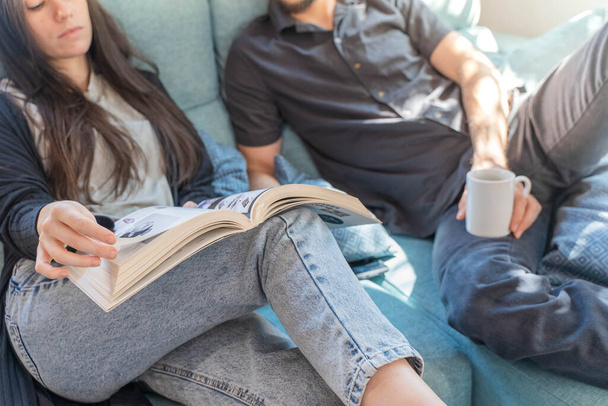 Coronavirus. Un couple assis sur le canapé en quarantaine à la maison, pendant le coronavirus. Couple à la maison sur le canapé et regarder un livre et parler. À la maison. Reste à la maison.  - Photo, image