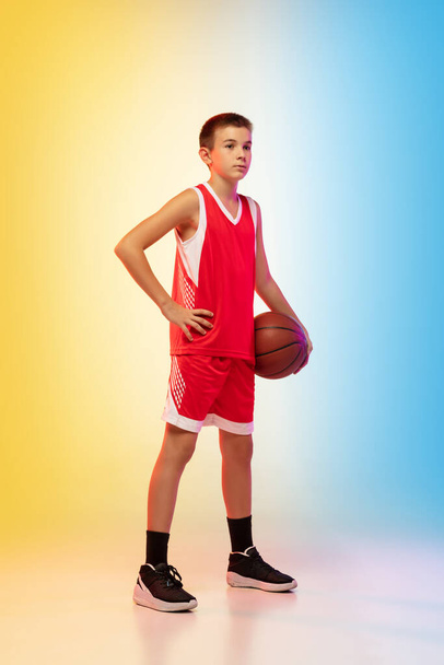 Full length portrait of a young basketball player with ball on gradient background - Fotó, kép