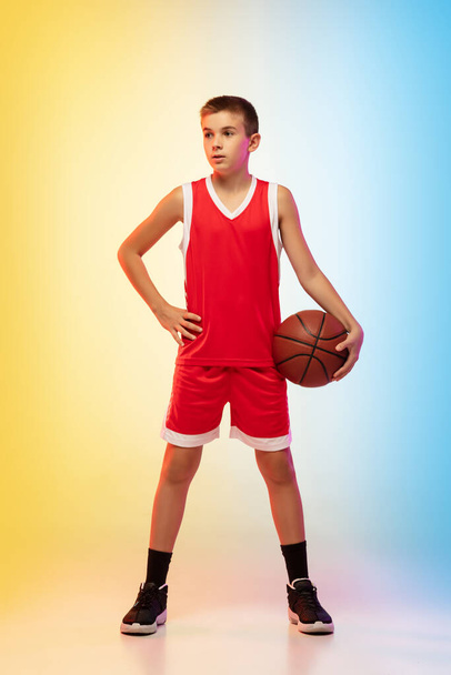 Full length portrait of a young basketball player with ball on gradient background - Fotografie, Obrázek