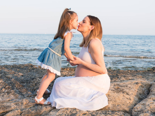 Έγκυος μητέρα και κόρη φιλιούνται στην παραλία - Φωτογραφία, εικόνα