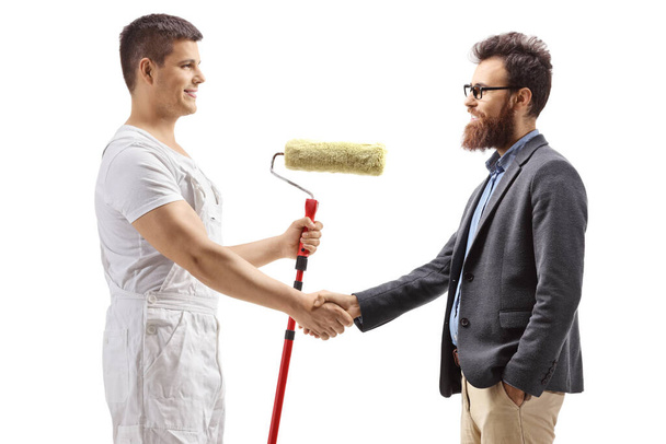 Painter with a roller painter shaking hands with a bearded man isolated on white background - Photo, image