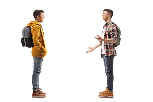 Full length profile shot of two male teenage students having a conversation isolated on white background - Fotoğraf, Görsel