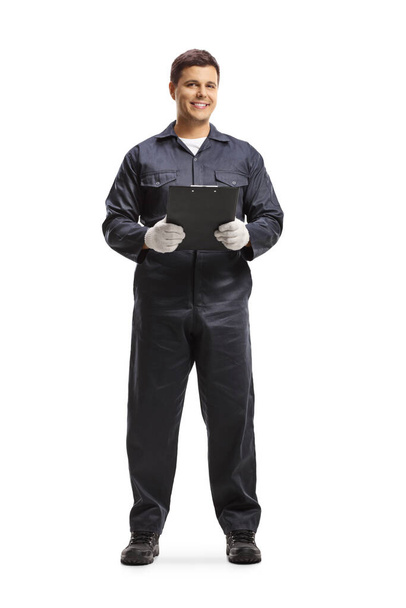 Full length portrait of auto mechanic worker in a navy blue uniform holding a clipboard isolated on white background - Zdjęcie, obraz