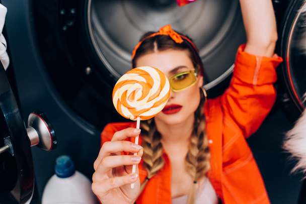 sweet lollipop in hand of fashionable woman in sunglasses on blurred background - Foto, imagen