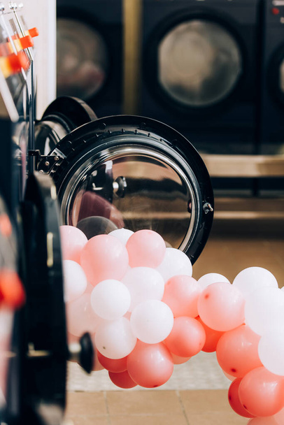 Çamaşırhanedeki modern çamaşır makinelerinin yanında ön planda bulanıklık olan balonlar. - Fotoğraf, Görsel