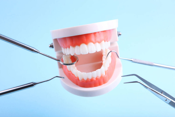 modelo de dientes e instrumentos dentales levitan en el aire sobre un fondo azul - Foto, Imagen