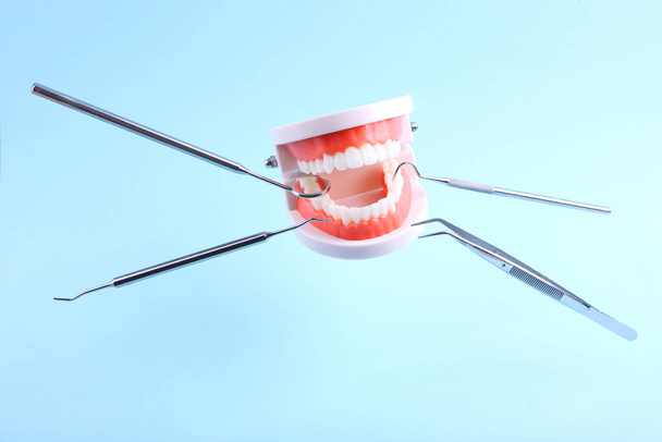 μοντέλα δοντιών και οδοντιατρικά όργανα αιωρείται στον αέρα σε μπλε φόντο - Φωτογραφία, εικόνα
