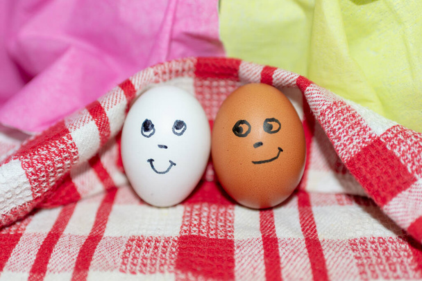 Концепція дружби. Смішні два яйця в різних кольорах разом. Фотографія вашого дизайну. Яйця на біло-червоному картатому рушнику. Закрити
. - Фото, зображення