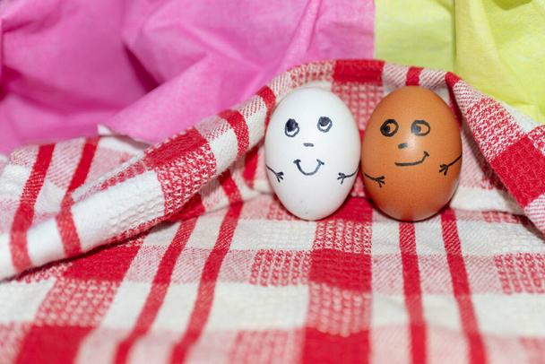 Concept d'amitié. Drôle deux œufs de couleurs différentes ensemble. Photo pour votre design. Œufs sur une serviette à carreaux blanc-rouge.Fermer. - Photo, image
