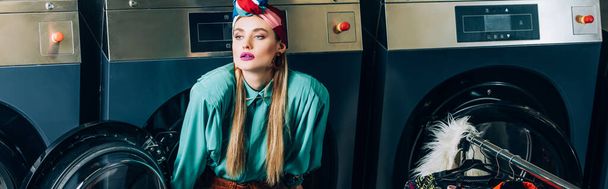donna giovane ed elegante in turbante vicino lavatrici in lavanderia moderna, banner - Foto, immagini