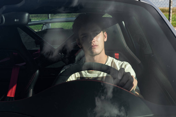 a young man sits behind the wheel of an expensive sports car. guy driving a car. - Valokuva, kuva