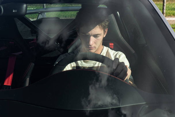 a young man sits behind the wheel of an expensive sports car. guy driving a car. - Foto, immagini