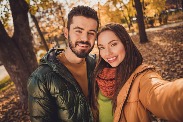 Portrait of affectionate charming couple girl guy make selfie in fall town center park wear september coats scarf - Foto, Bild