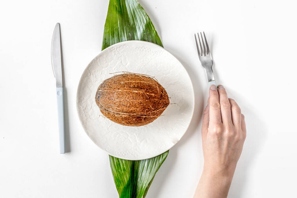 kokosnoot op plaat bovenaanzicht op witte achtergrond - Foto, afbeelding