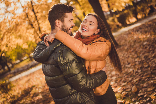 Photo of passionate bonding couple guy hug cuddle laughing girlfriend in fall october foliage park wear season coats - Photo, Image