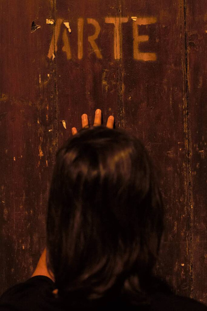彼女の背中の女性は、木製のドアの前に書かれている"アート" - 写真・画像