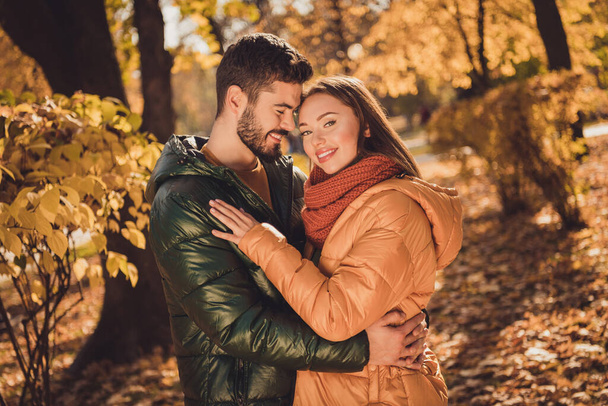 Photo of positive charming affectionate couple guy hug his girlfriend in autumn september outdoors park - Fotoğraf, Görsel