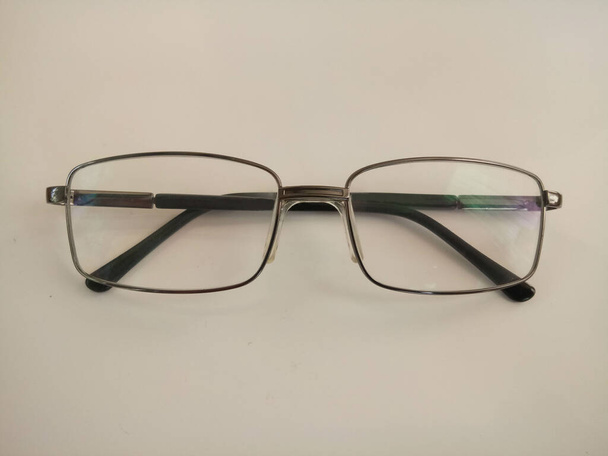 óculos em uma moldura de metal escuro em um fundo branco - Foto, Imagem