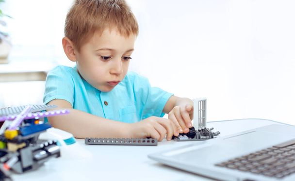 Anaokulu çocuğu ev ödevini yaparken robotik bir cihaz yapmaya çalışıyor. Çevrimiçi eğitim, E-öğrenme kavramı, dizüstü bilgisayarla mesafe iletişimi - Fotoğraf, Görsel
