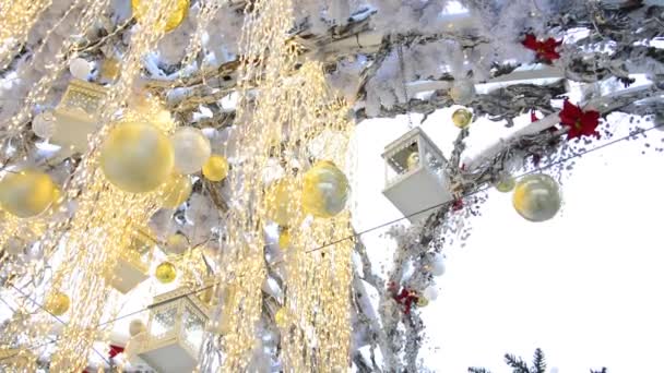 Kerst structuur in de vorm van een boog versierd met gouden ballen en lichtgevende bloemenslingers ontwikkelen in de wind op een straat in Moskou. - Video