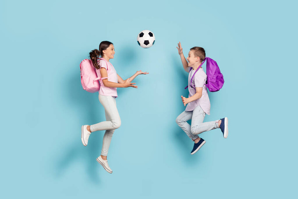 Full length body size view of two attractive small little cheerful friends friendship jumping play soccer cup goal throwing ball hobby leisure isolated blue pastel color background - Фото, зображення