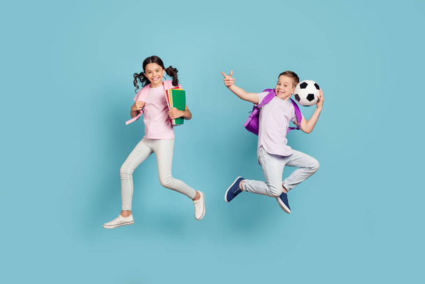 Full length body size view of his he her she attractive small little cheerful friends friendship jumping having fun playing football cup goal free time isolated blue pastel color background - 写真・画像