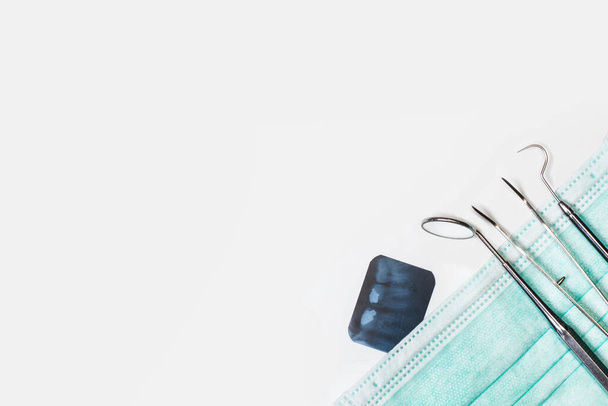 Dentist tools on a surgery mask and on a white background with copy space in a top view - Photo, Image