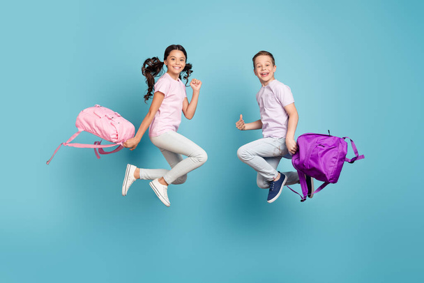 Full length body size view of his he her she nice attractive small little cheerful best friends friendship jumping having fun good mood free time leisure vacation isolated blue pastel color background - 写真・画像