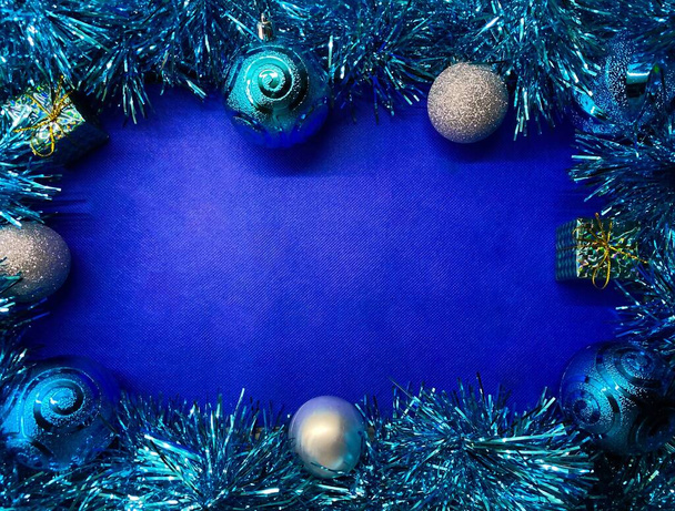 Leuchtend blauer Weihnachtshintergrund aus Lametta und Weihnachtskugeln. Freiraum. - Foto, Bild