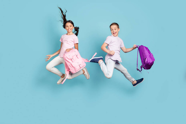 Full length body size view of his he her she nice attractive small little cheerful best buddy fellow jumping having fun after classes fooling leisure free time isolated blue pastel color background - Фото, изображение