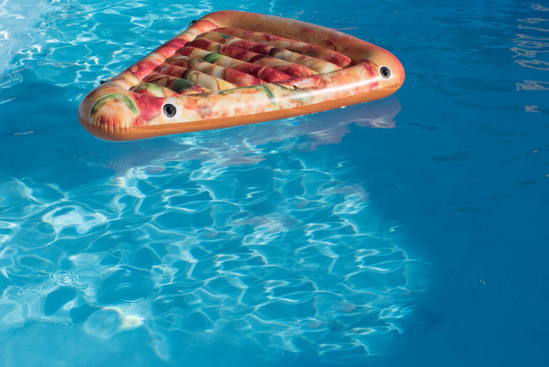 Pizzan muotoinen kelluva uima-altaan vedessä. Kopiotila - Valokuva, kuva