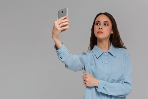 Beautiful young woman is making selfie photo with smartphone. - Фото, зображення
