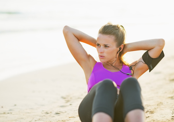 Fitness young woman doing abdominal crunch on beach - Φωτογραφία, εικόνα