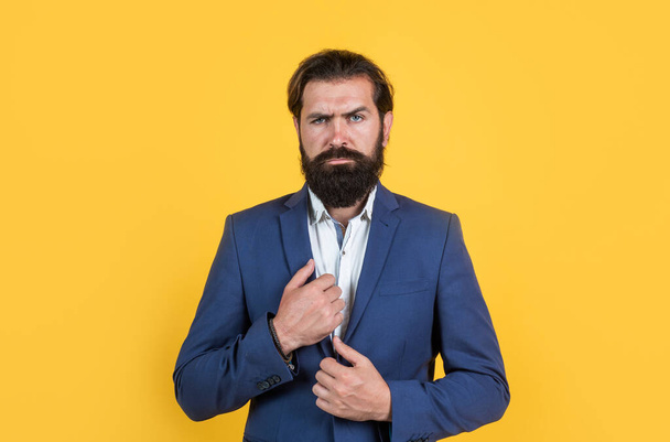 Portrait of business man arranging his business jacket on yellow background having beard and moustache, office fashion - Photo, image