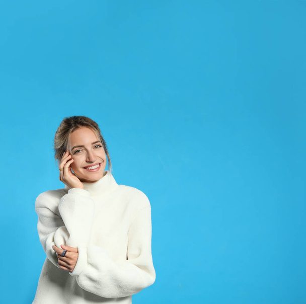 Beautiful young woman wearing knitted sweater on light blue background. Space for text - Fotografie, Obrázek