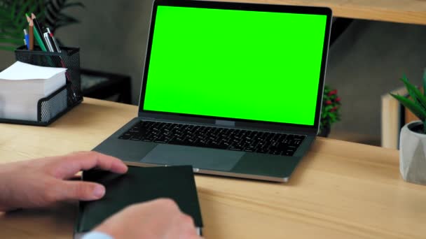 Koncept notebooku zelené obrazovky: on-line dálkové vzdělávání prostřednictvím webové kamery videohovory konference. Muž student v domácí kanceláři sedí tabulka studie zapisuje informace s perem do notebooku - Záběry, video