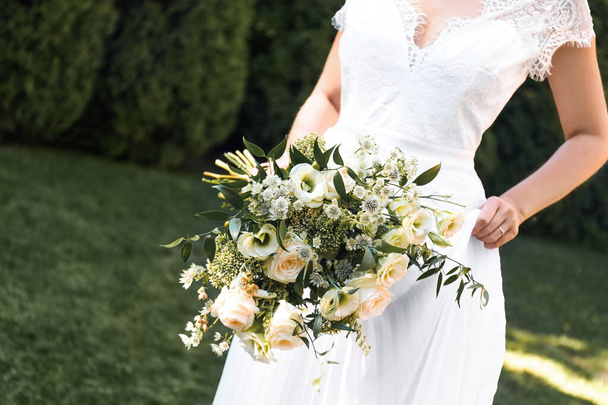 Bride in beautiful wedding dress with bouquet outdoors, closeup - Foto, Imagen