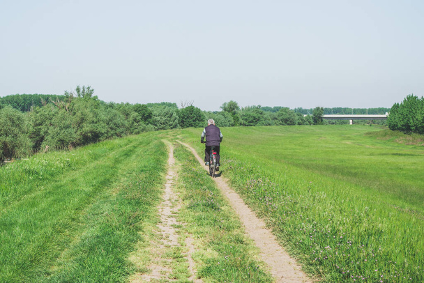 senior man riding bicycle on rural road - Photo, image