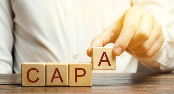 Businessman puts wooden blocks with the word CAPA. Corrective and Preventive action plans. Business management concept. Strategy and efficiency. Improving organizational processes. Performance - Fotoğraf, Görsel