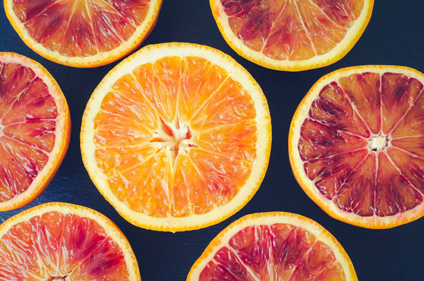 Sliced blood oranges texture. Citrus background. Cut ripe juicy Sicilian Blood oranges fruits on back background. Top view. - Photo, Image