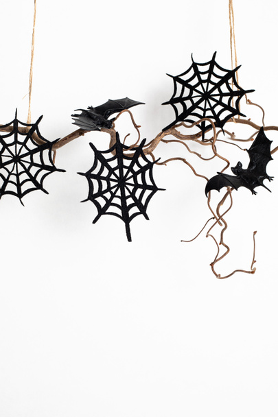 Minimale Halloween-Dekoration, die an einem Ast über einer weißen Wand hängt. Grußkarte, Konzept für die Weihnachtsdekoration. Kopierraum - Foto, Bild
