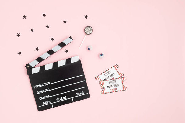 Movie clapperboard and halloween decoration over pink background. Horror movie night, halloween party invitation. Top view, copy space, mockup - Photo, Image