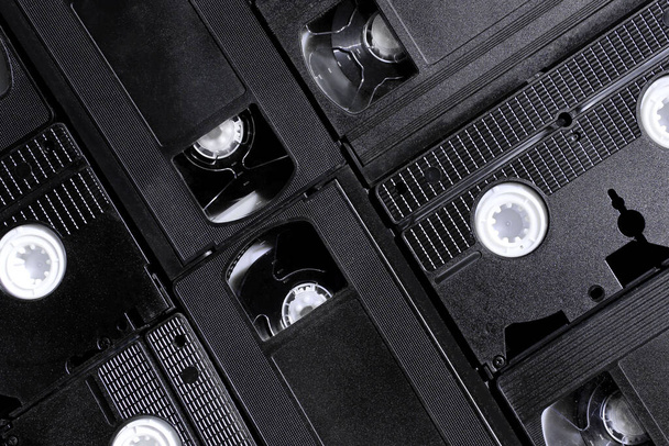 Обрезанный снимок черных видеокассет, вид сверху, горизонтальный снимок. Абстрактный ретро фон. - Фото, изображение