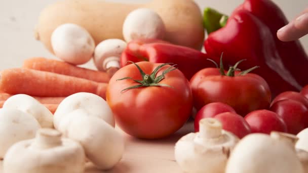 Die weißen Hände eines Mannes pflücken eine bunte Tomate aus verschiedenen Gemüsesorten. Stop-Motion. - Filmmaterial, Video