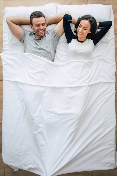 寝る時間だ。家族は寝ている。愛の美しい若いカップルは、大きな白いベッドの上に横たわっていると休んでいる。夫と妻はベッドで一緒に。トップ表示写真 - 写真・画像