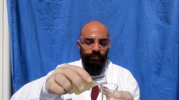 Der professionelle kaukasische Chemiker oder Wissenschaftler mit Brille, Handschuhen, Krawatte und Kleid führt ein chemisches Experiment durch und betrachtet die Kameraposition. Halten Sie einen Beuta und einen Beker mit einer Säure und einer Lauge. Zeitlupe - Filmmaterial, Video