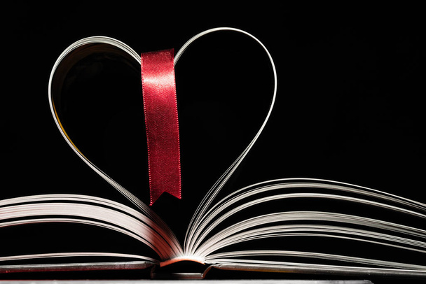 Libro abierto con tapa de libro rojo sobre fondo negro. Páginas en forma de corazón. Primer plano. - Foto, Imagen