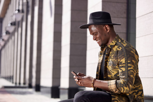 good-looking black male use smartphone while he is walking - Valokuva, kuva