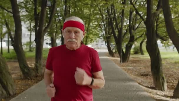 Чоловік старший біжить по дорозі в парку. Зрілий бігун тренується, слухаючи музику
 - Кадри, відео